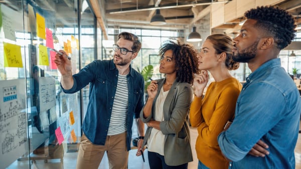 business colleagues standing for a meeting near a memo board