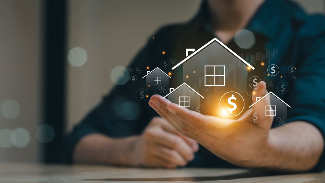 hand holding a model of a home with dollar sign l