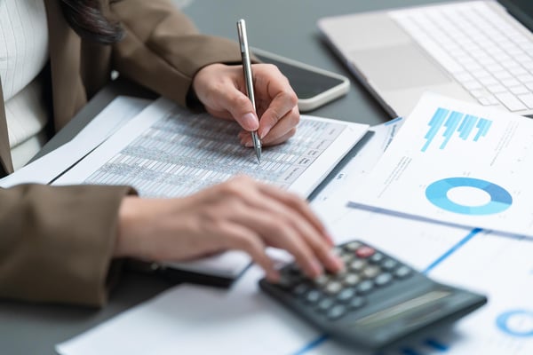 hands using a calculator and writing on financial documents