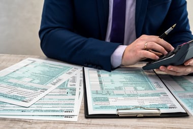 male hands holding a calculator and tax documents