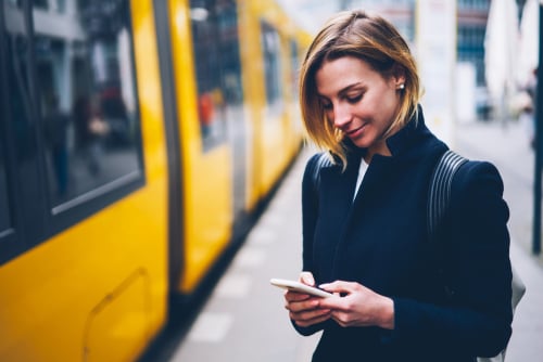 woman looking at cell phone near metro train