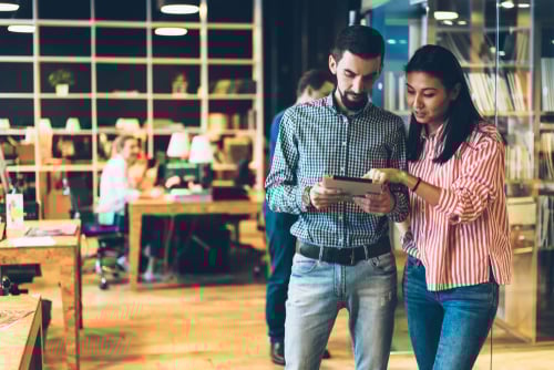 man and woman in office reviewing information on a device
