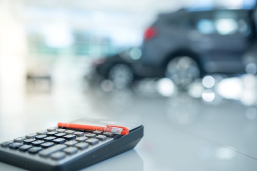 calculator with auto dealership in the background