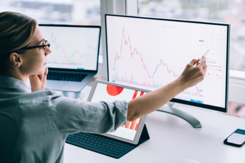 woman at desk looking a various computer monitors