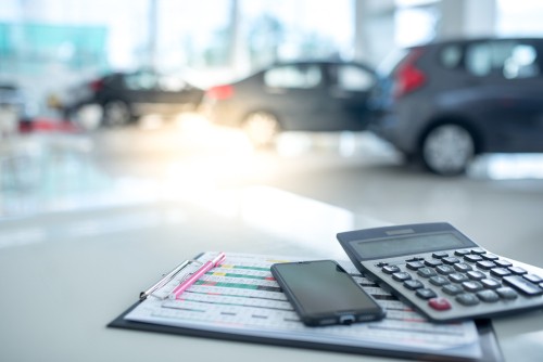 Images in a car showroom with calculators and smartphones placed on a table