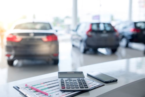 vehicles in an auto showroom with calculator and finance papers