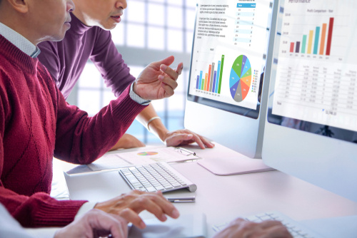 businessmen looking at a computer monitor with financial graphs