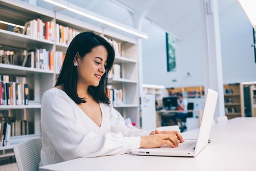 woman in library working on laptop