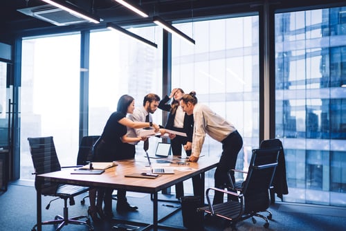 employees standing up at a conference table looking at a screen