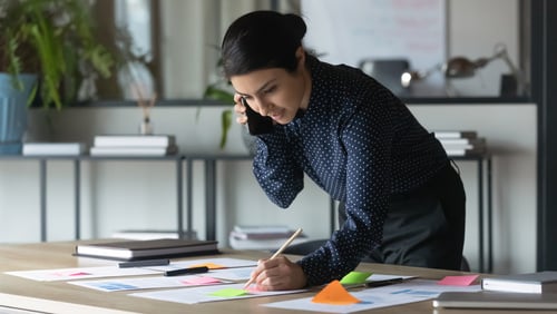 business woman reviewing documents while talking on phone
