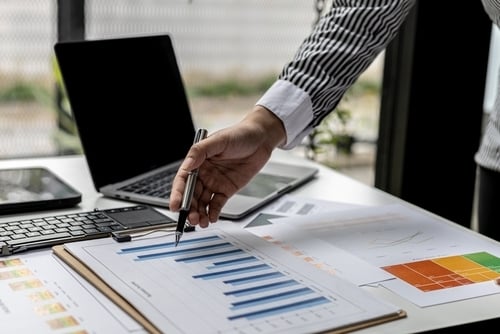financial graphs on a desk with hand pointing to the charts