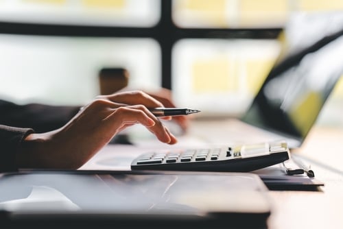 hand with pen, calculator and laptop screen