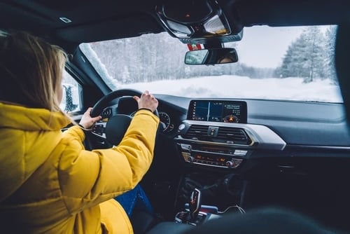 auto interior and woman in yellow coat driving