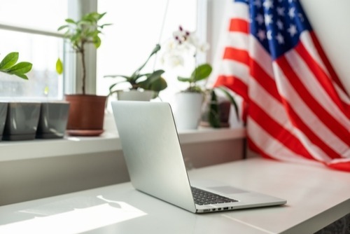 laptop on desk with flag in background