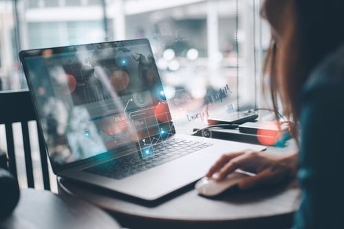 A person using a laptop with data analytics and world map graphics overlaid 