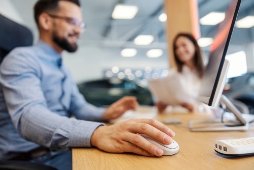 business professionals at a desk with computer at car dealership