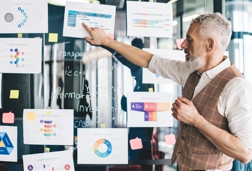 senior man pointing to business papers on a glass wall
