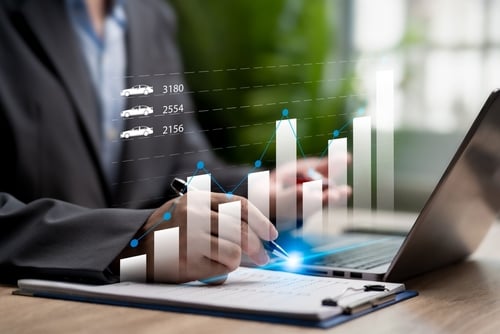 businessman with graphs on a laptop showing automobile icons