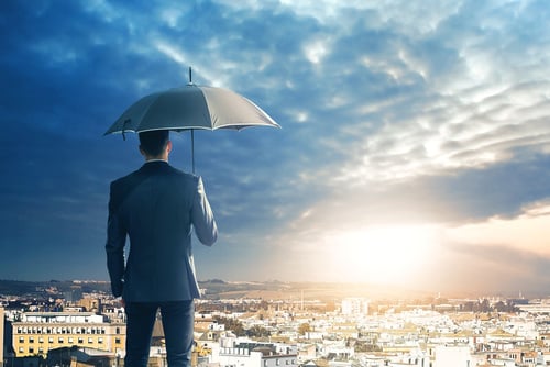 businessman with umbrella overlooking a city with stormy weather ahead