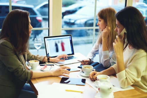 women at a business lunch meeting looking at laptop screen
