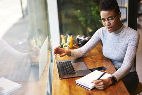 woman at desk with laptop and notebook and pen