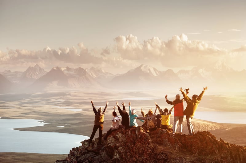 people cheering at top of mountain peak