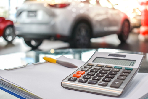calculator and clipboard with dealership showroom in background