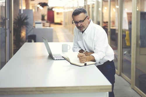 business professional looking at notes and laptop